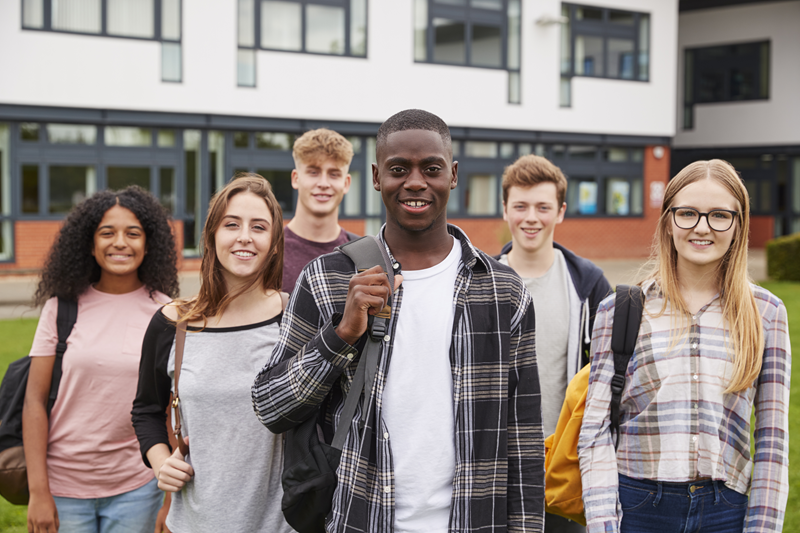 Grupo de estudantes do ensino médio em frente a escola internacional durante programa de High School no exterior.